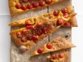 Saftige focaccia mit tomaten und Rosmarin, auf einem Holzbrett mit Mehl bestäubt.