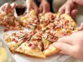Hände greifen nach leckeren Stücken einer glutenfreien Pizza. Ein tolles glutenfreies Pizza Rezept für alle!