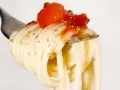 Eine Gabel mit Spaghetti, belegt mit Tomaten und Kräutern. Ein Vorgeschmack auf die besten italienischen Pasta Rezepte.
