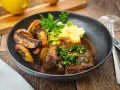 Ein Teller mit dem originalen Ossobuco-Rezept, dazu Kartoffelpüree und geröstete Kartoffelspalten.