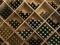 Weinregal mit vielen Flaschen Wein. Die Frage, wie lange kann man Wein lagern, hängt von der Sorte ab.