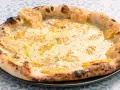Eine köstliche Pizza Formaggi mit geschmolzenem Käse und knusprigem Rand, serviert auf einem Teller mit blau-weißem Muster.