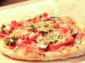 Eine köstliche Pizza mit Pilzen und Tomaten auf einem luftigen pizzateig mit lievito madre, bereit zum Genießen.