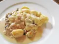 Gnocchi al forno mit cremiger Käsesauce, Pilzen und Schinken auf einem weißen Teller.