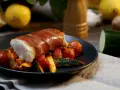Kabeljau Saltimbocca: ein zartes Fischfilet, umwickelt mit luftgetrocknetem Schinken, serviert auf einem Bett aus Kirschtomaten und Zucchini.