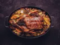 Brathähnchen mit Kartoffeln, Karotten, Orangen und Knoblauch. Ein Festmahl, das perfekt zu einem Glas Wein zu Ente passt.