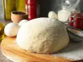 Frischer, fluffiger Teig für schnellen Pizzagenuss liegt bereit. Zutaten wie Eier, Öl und Gewürze deuten auf eine köstliche Pizza hin.