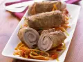 Drei köstliche kalbsrouladen italienisch auf einem Bett aus Gemüse. Eines ist aufgeschnitten und zeigt die saftige Füllung.