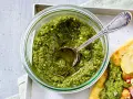 Frisches Basilikum Pesto in einem Glas, mit einem Löffel darin. Perfekt für Pasta oder Bruschetta.