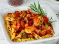 Penne-Nudeln mit Garnelen, Auberginen und Tomaten, garniert mit Rosmarin und Chiliflocken. Ein köstliches Gericht, das Lust auf mehr macht.