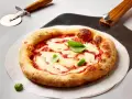 Frisch gebackene Pizza Margherita mit geschmolzenem Mozzarella und Basilikum. Daneben liegen ein Pizzaschneider und eine Pizzaschaufel, bereit, den perfekten pizzateig ausrollen.