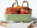 Saftige peperoni ripieni, gefüllt mit Hackfleisch und Reis, in einer grünen Auflaufform.
