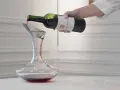 Roter Wein wird aus einer Flasche in einen Dekanter gegossen. Der Wein ist verkorkt und bereit zum Genießen.