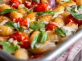 Gebackene Gnocchi mit Kirschtomaten, Basilikum und Parmesan. So sehen köstliche Gnocchi aus, wenn sie im Ofen mit frischen Zutaten zubereitet werden.