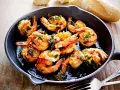 Saftige Garnelen in Knoblauchöl, ein Klassiker der italienischen scampi rezepte. Dazu Baguette.