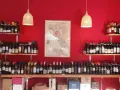 Regal voller italienischer Weinsorten vor roter Wand. Eine Karte Italiens mit Weinregionen hängt zentral.