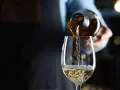 Weißwein wird in ein Glas gegossen. Die natürlichen wein zutaten sind im Glas sichtbar.
