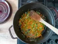 Würziges Sofrito Rezept: Karotten, Sellerie und Zwiebeln werden in einem gusseisernen Topf angedünstet.