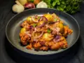 Herzhafte Salsiccia-Rezepte ohne Pasta: Kartoffeln, rote Zwiebeln und Speck in einer würzigen Tomatensauce, garniert mit frischen Kräutern.