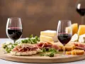Perfekte Snacks zum Rotwein: Käse, Schinken und Brot auf einem Holzbrett, dazu zwei Gläser Rotwein.