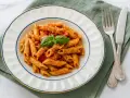 Penne mit cremigem Pesto Rosso, garniert mit Basilikum und Parmesan. Ein köstliches Gericht, das Lust auf mehr macht.