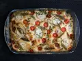 Frisch gebackene Focaccia mit Kirschtomaten, Zwiebelringen und Kräutern belegen.