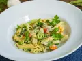 Penne mit cremigem Pesto, Spargel, Erbsen, Brokkoli und Karotten, garniert mit Parmesan und frischen Kräutern.