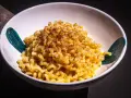 Cremige Pasta Alfredo, bestreut mit Gewürzen, in einer weißen Schüssel mit türkisfarbenen Akzenten.