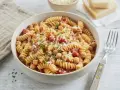 Eine Schüssel Fusilli-Nudeln mit Kichererbsen, Tomaten und Parmesan, garniert mit Petersilie.