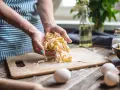 Frische Pasta aus dem perfekten pasta teig rezept. Hände halten die Bandnudeln, Mehl und Eier liegen bereit.