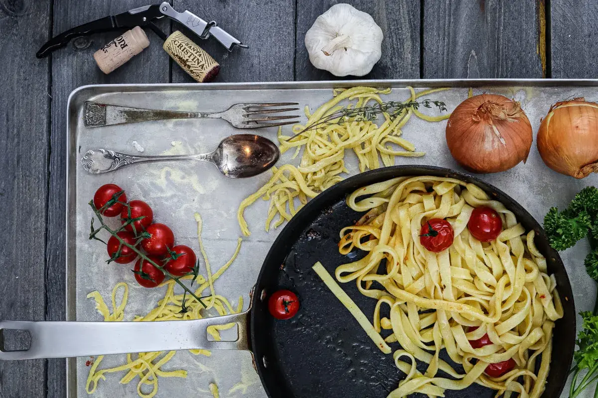 Frische Nudeln aus Hartweizengries, Tomaten, Zwiebeln und Knoblauch auf einem Blech. Ein Festmahl für Genießer!