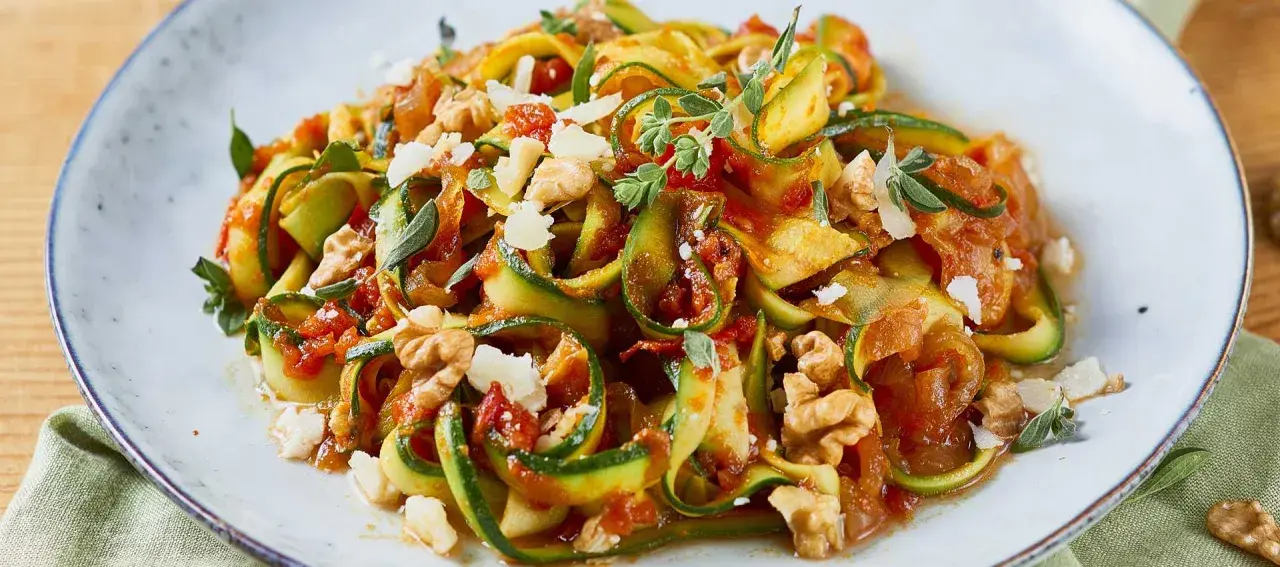 Zucchini-Nudeln mit Tomatensoße, Walnüssen und Parmesan. Ein leichtes Gericht, perfekt für Zucchini Rezepte.