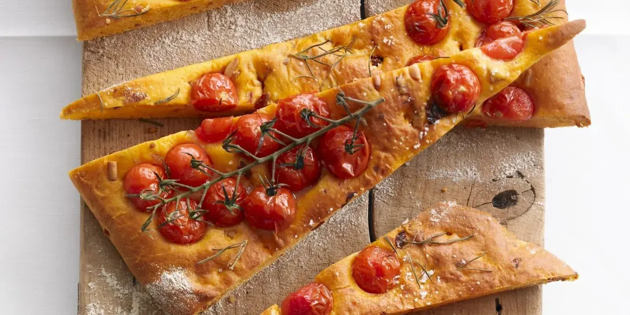 Saftige focaccia mit tomaten und Rosmarin, auf einem Holzbrett mit Mehl bestäubt.