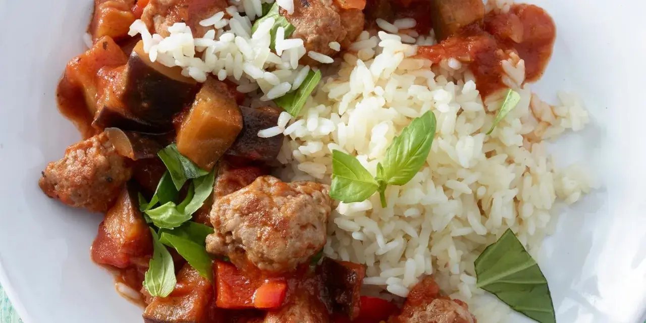 Herzhafte Salsiccia-Zubereitung in der Pfanne mit Auberginen, Paprika und Reis, garniert mit frischem Basilikum.