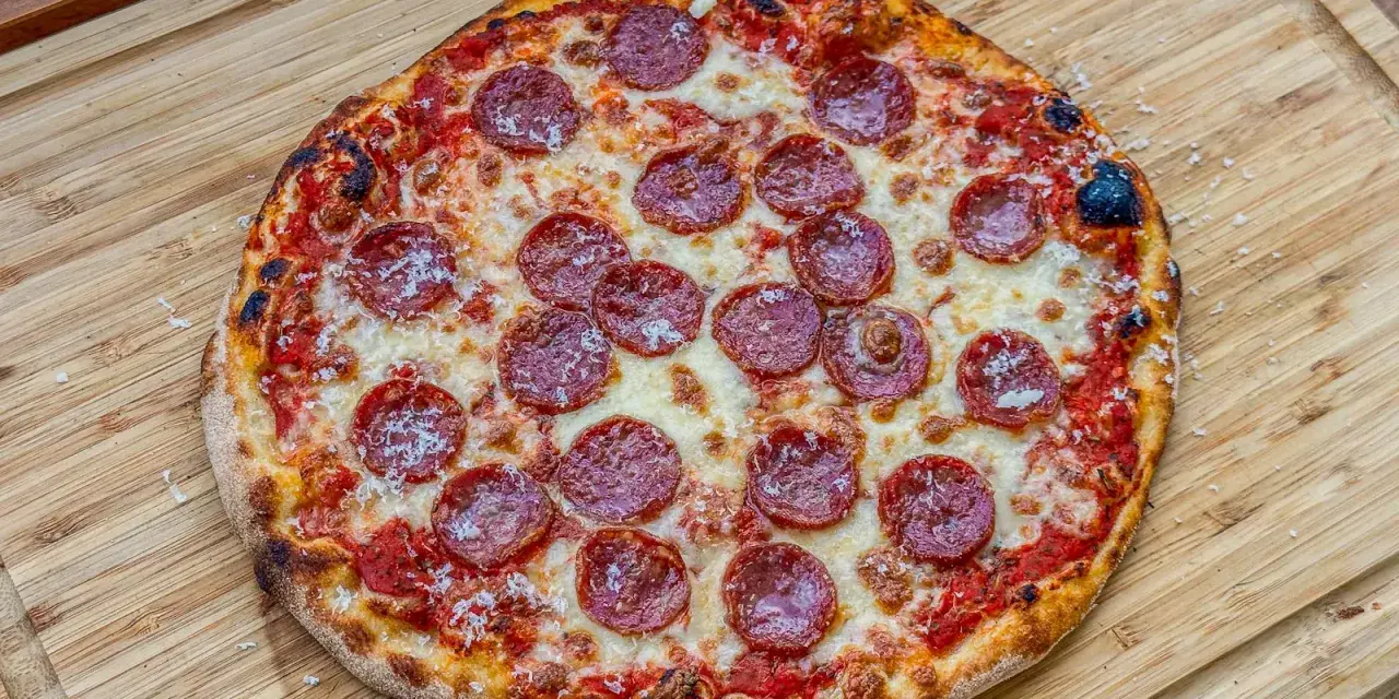 Eine köstliche Pizza Salami mit geschmolzenem Käse und knusprigem Rand liegt auf einem Holzbrett.