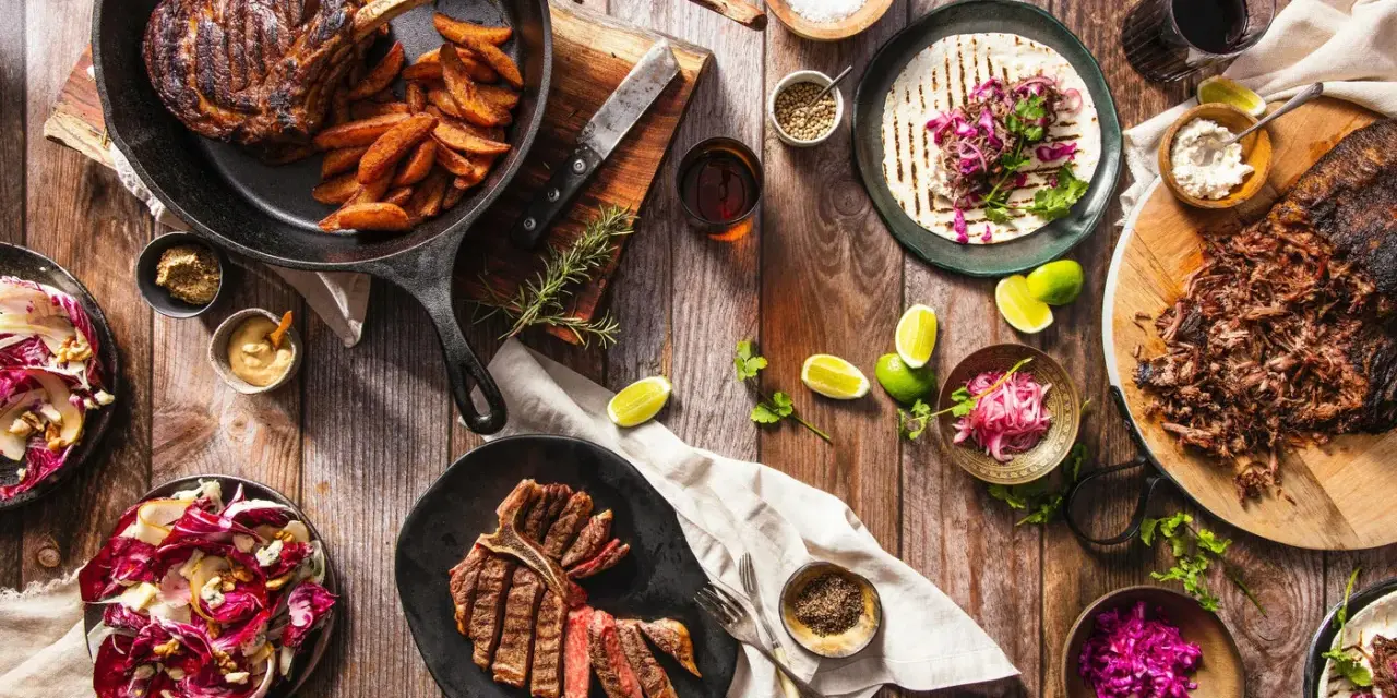 Ein Sommelier wählt den perfekten Wein zu saftigen Steaks, Beilagen und frischen Salaten.