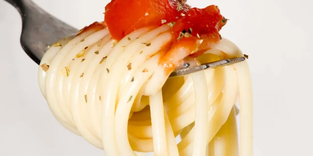 Eine Gabel mit Spaghetti, belegt mit Tomaten und Kräutern. Ein Vorgeschmack auf die besten italienischen Pasta Rezepte.