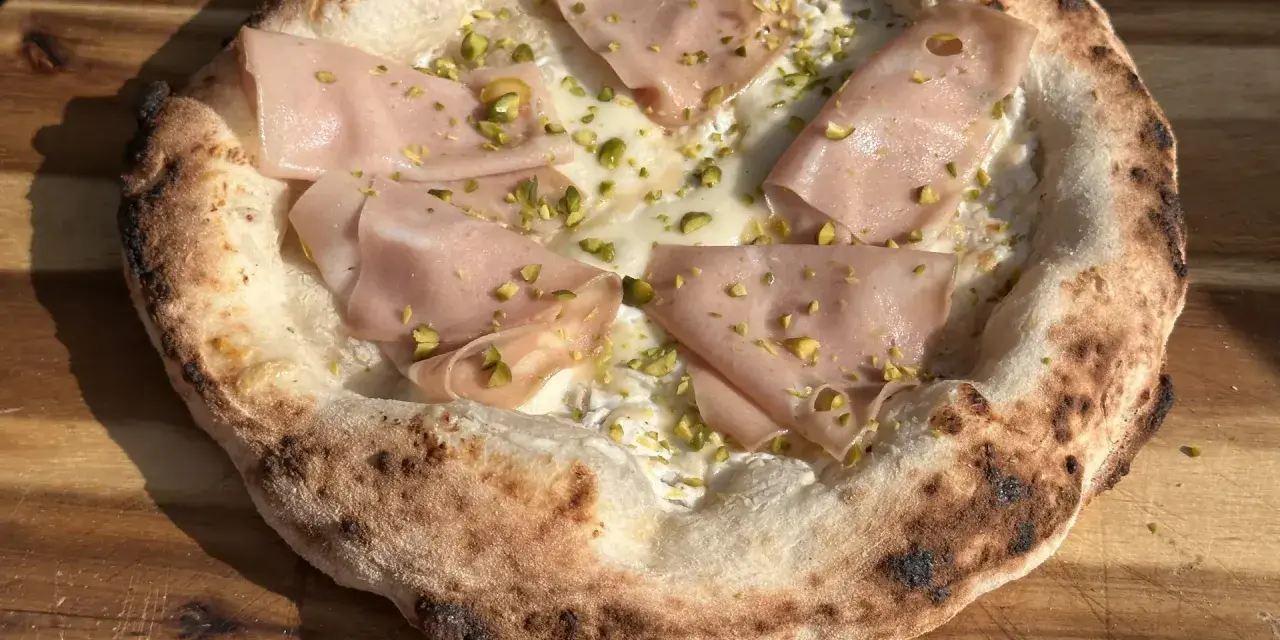 Frisch gebackener Pizzateig mit Mortadella und Pistazien. Ein Genuss, der das Pizzabacken zu einem Erlebnis macht.