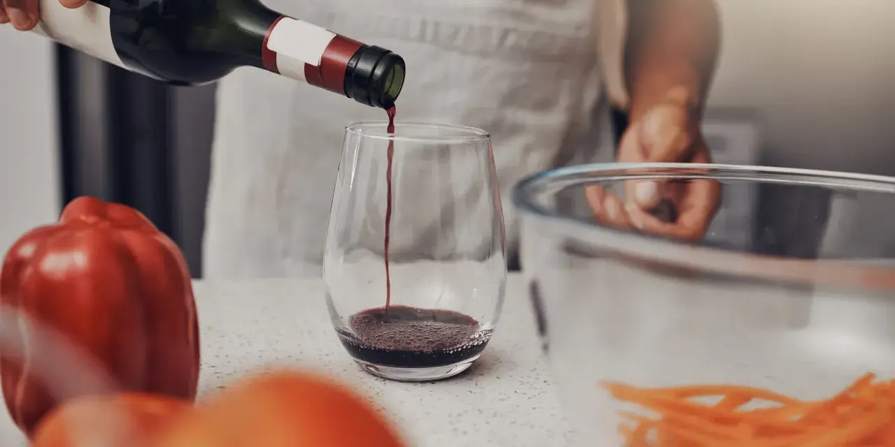 Rotwein wird in ein Glas gegossen, bereit für die Zubereitung eines köstlichen Gerichts. Die Frage, welchen Wein zum Kochen, ist nun beantwortet.