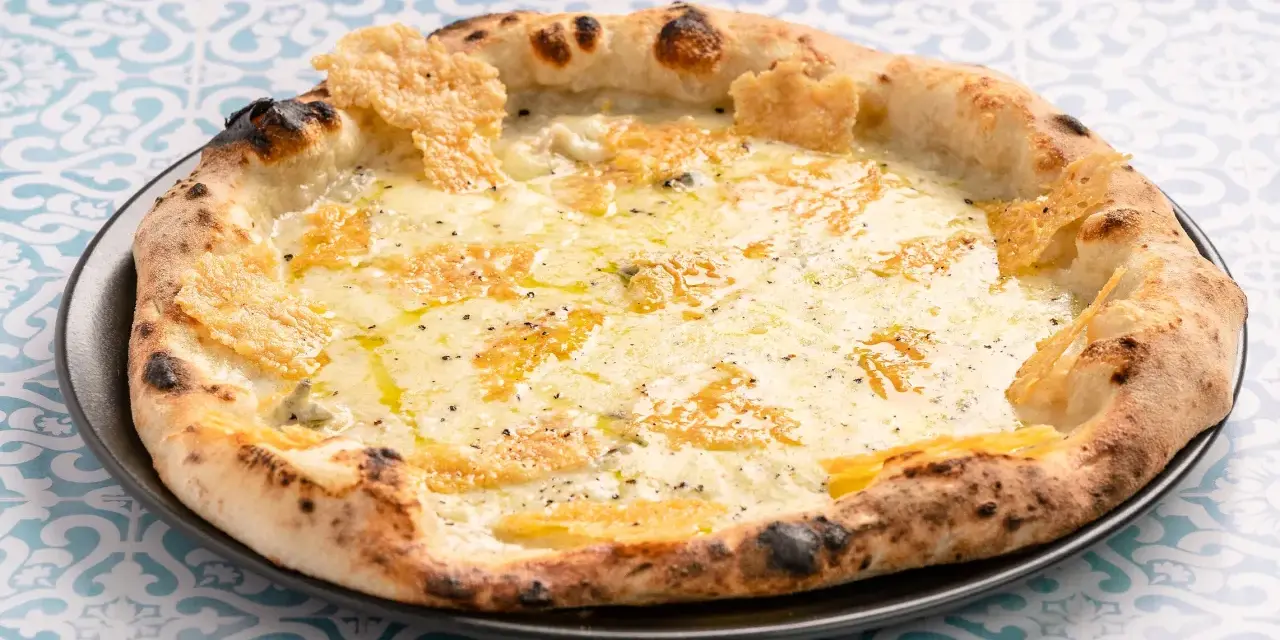 Eine köstliche Pizza Formaggi mit geschmolzenem Käse und knusprigem Rand, serviert auf einem Teller mit blau-weißem Muster.