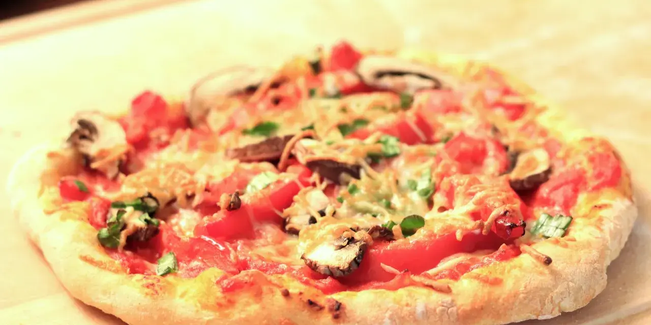 Eine köstliche Pizza mit Pilzen und Tomaten auf einem luftigen pizzateig mit lievito madre, bereit zum Genießen.