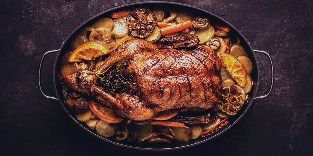 Brathähnchen mit Kartoffeln, Karotten, Orangen und Knoblauch. Ein Festmahl, das perfekt zu einem Glas Wein zu Ente passt.
