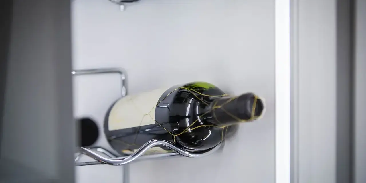 Eine Flasche Rotwein liegt auf einem Chromgestell. Der Wein ist bereits geöffnet, was man an der leichten Oxidation erkennen kann.