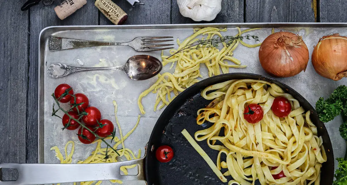 Frische Nudeln aus Hartweizengries, Tomaten, Zwiebeln und Knoblauch auf einem Blech. Ein Festmahl für Genießer!
