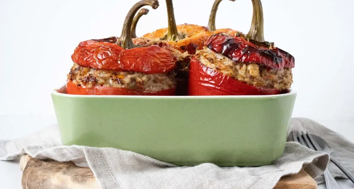 Saftige peperoni ripieni, gefüllt mit Hackfleisch und Reis, in einer grünen Auflaufform.