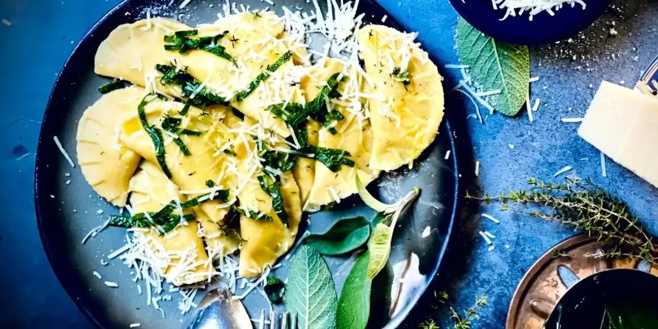 Frische Ravioli, ein italienisches Gericht, mit geriebenem Parmesan und Kräutern garniert. Das Ravioli-Teig Rezept italienisch ist hier perfekt umgesetzt.