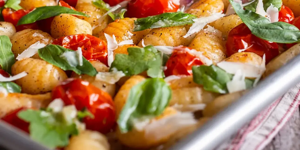 Gebackene Gnocchi mit Kirschtomaten, Basilikum und Parmesan. So sehen köstliche Gnocchi aus, wenn sie im Ofen mit frischen Zutaten zubereitet werden.