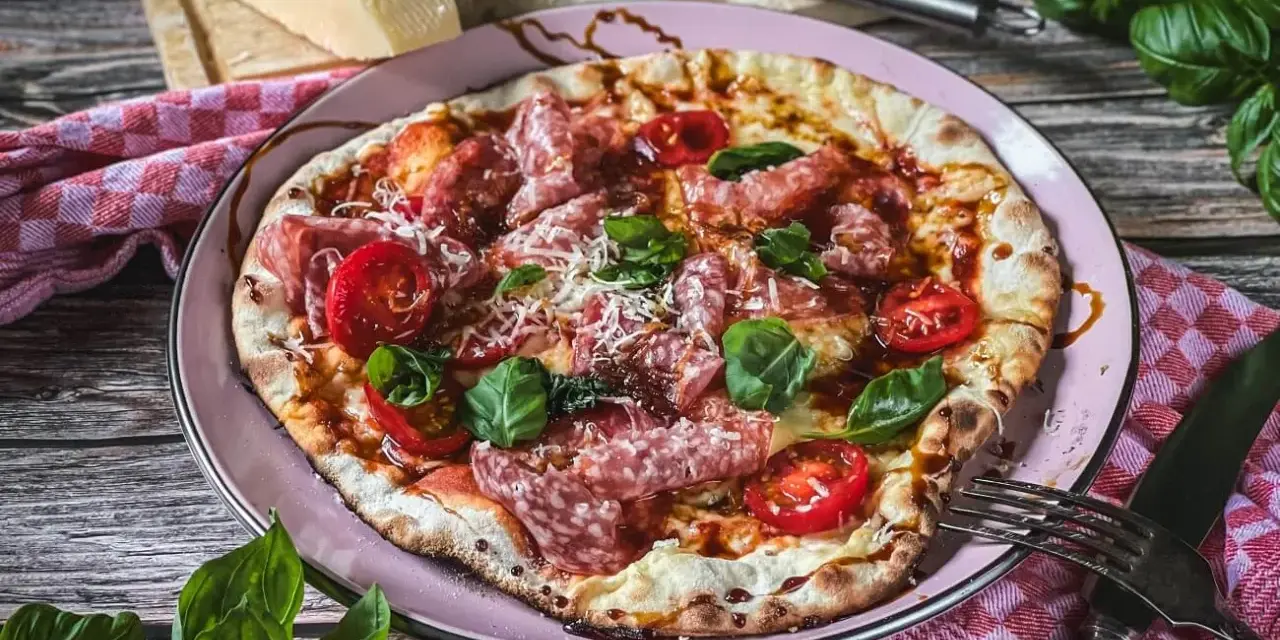 Leckere italienische Pizza mit Salami, Tomaten und Basilikum. Ein wahrer Genuss für alle, die italienische Rezepte lieben.
