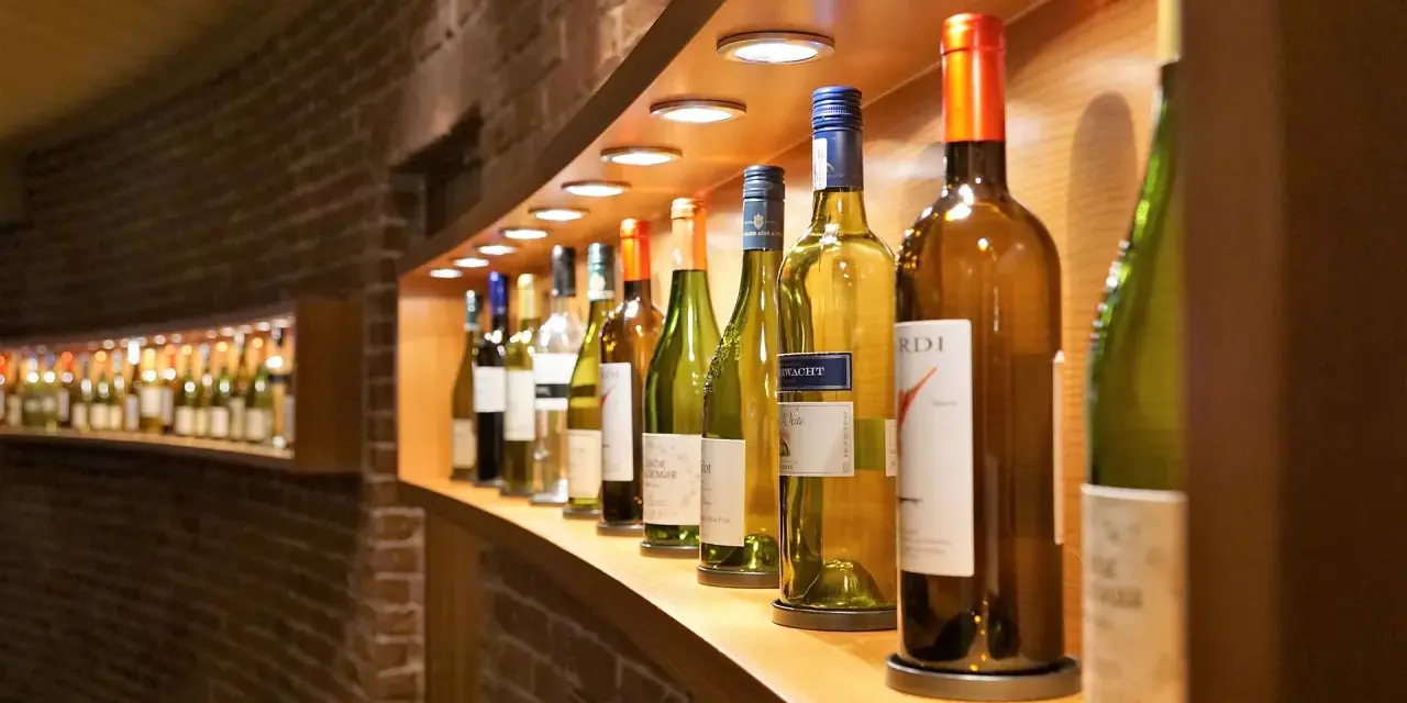 Eine Reihe von Wein- und Sektflaschen, einige davon sind bereits geöffnet. Die Frage, ob Rotwein schlecht werden kann, beschäftigt viele Weinliebhaber.