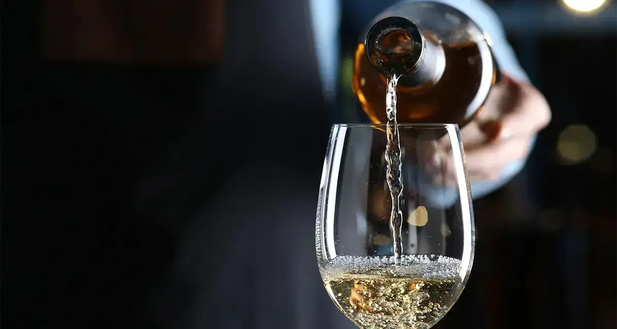 Weißwein wird in ein Glas gegossen. Die natürlichen wein zutaten sind im Glas sichtbar.